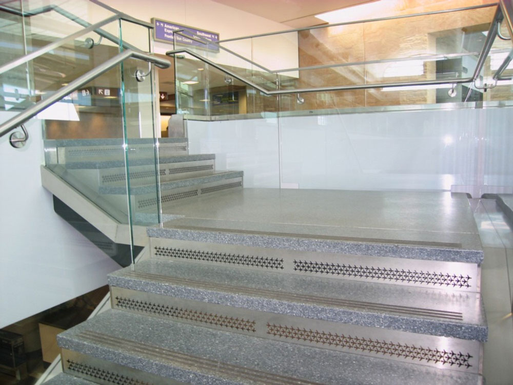 Tucson Airport. Stainless steel custom perf panel risers and glass guardrail.