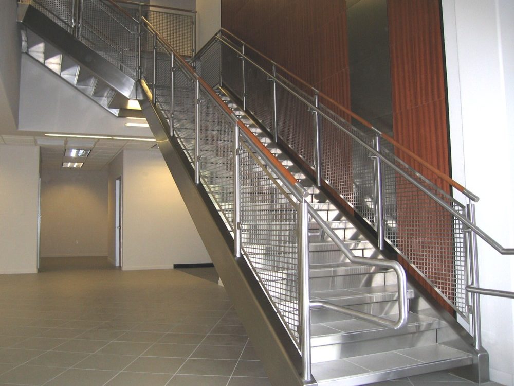 commercial building - stainless steel perf metal, railing, and stringer cladding. Stainless steel and wood cap rail.